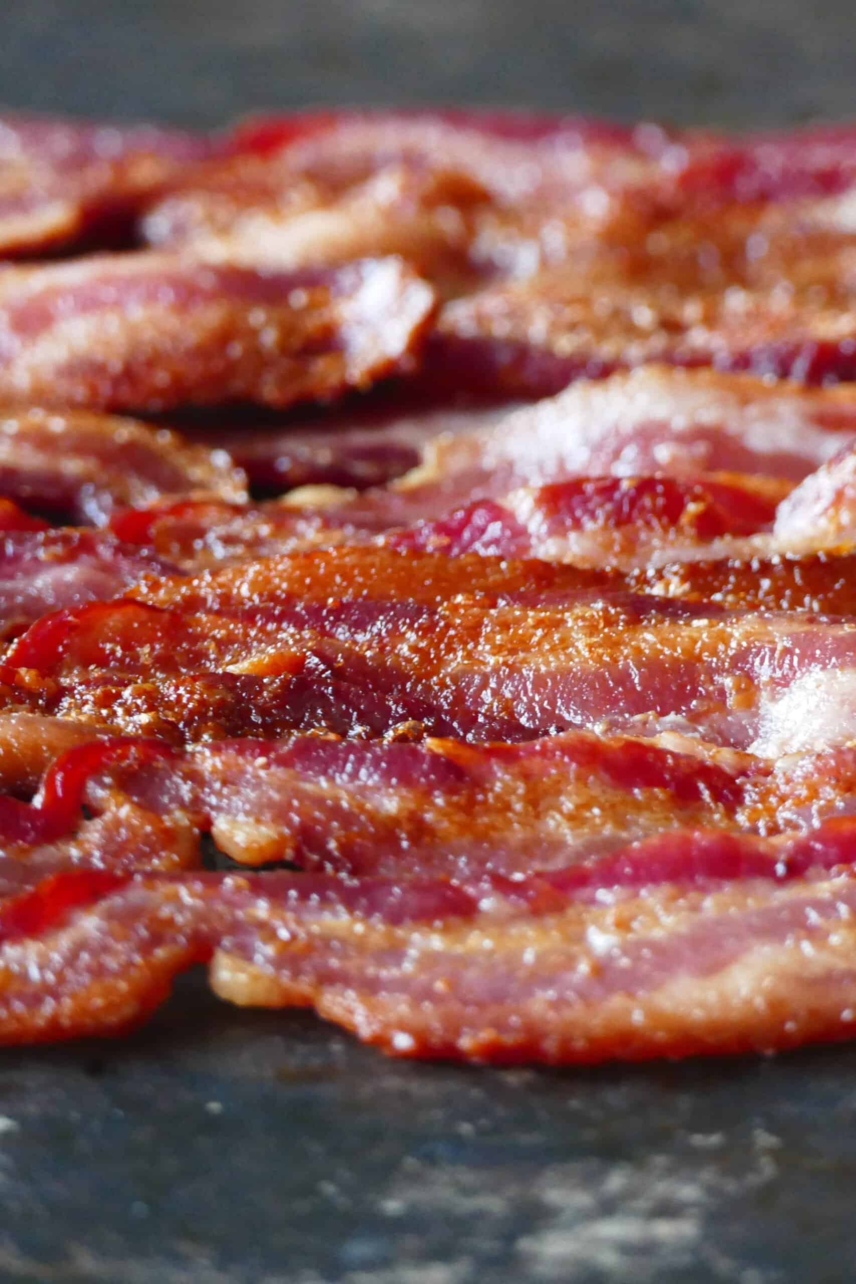 Air fryer bacon - Strips of cooked bacon on black background.