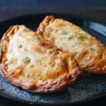 Two golden brown empanadas on blue plate