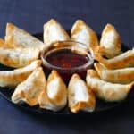 Golden gyoza potstickers in a circle with chili sauce in the middle