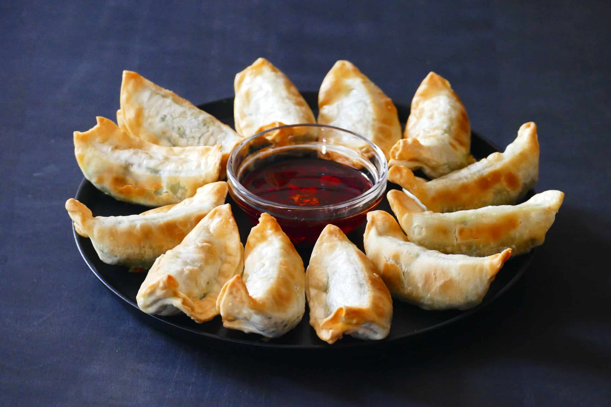 Golden gyoza potstickers in a circle with chili sauce in the middle