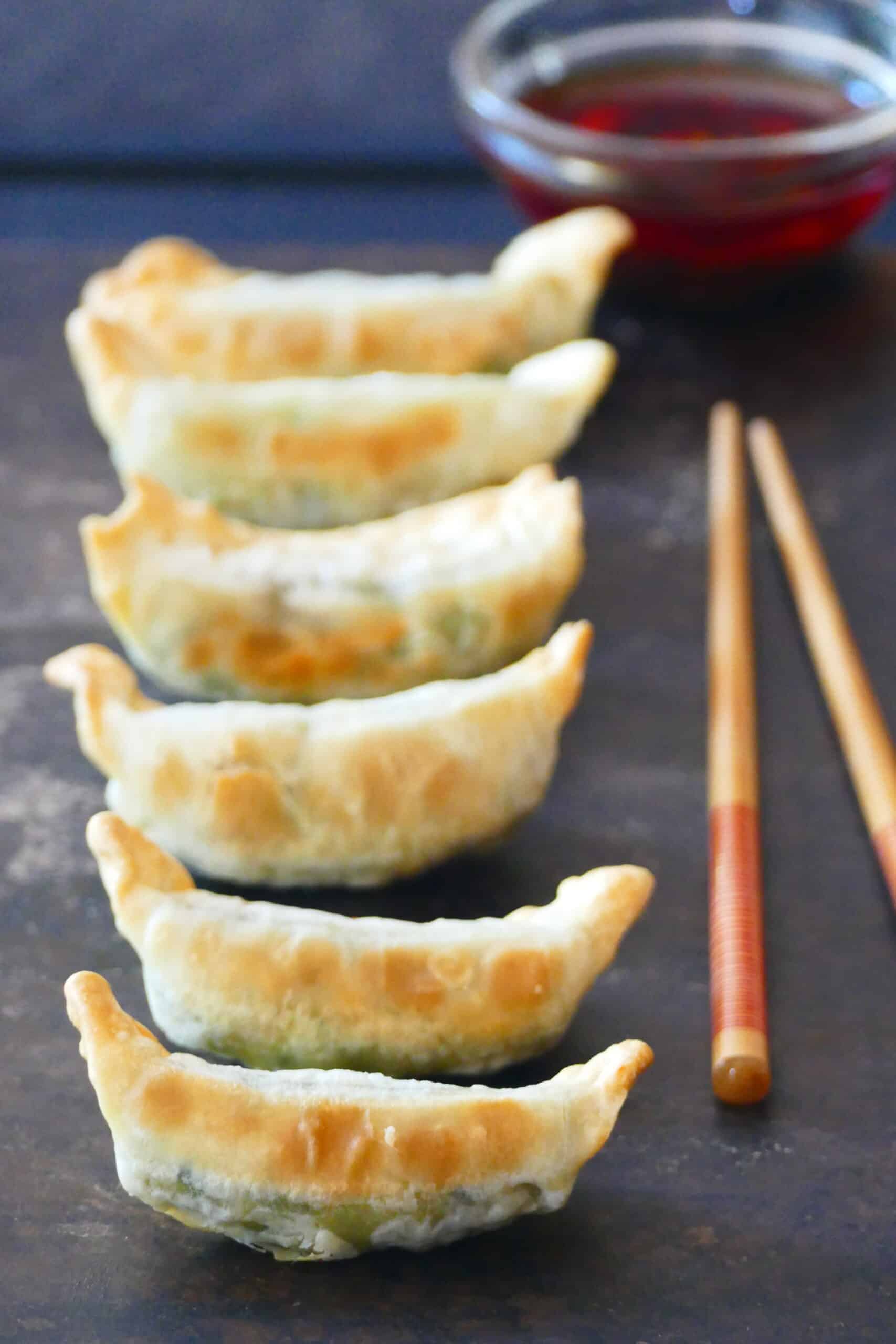 Air fryer frozen potstickers - Golden gyoza potstickers in a row with chili sauce and chopsticks