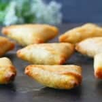 Golden mini samosas on dark background