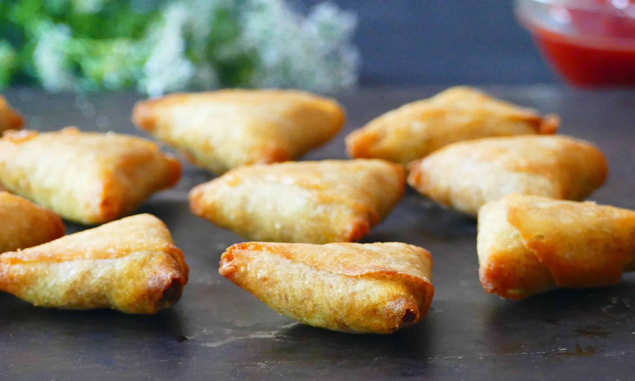 Golden mini samosas on dark background