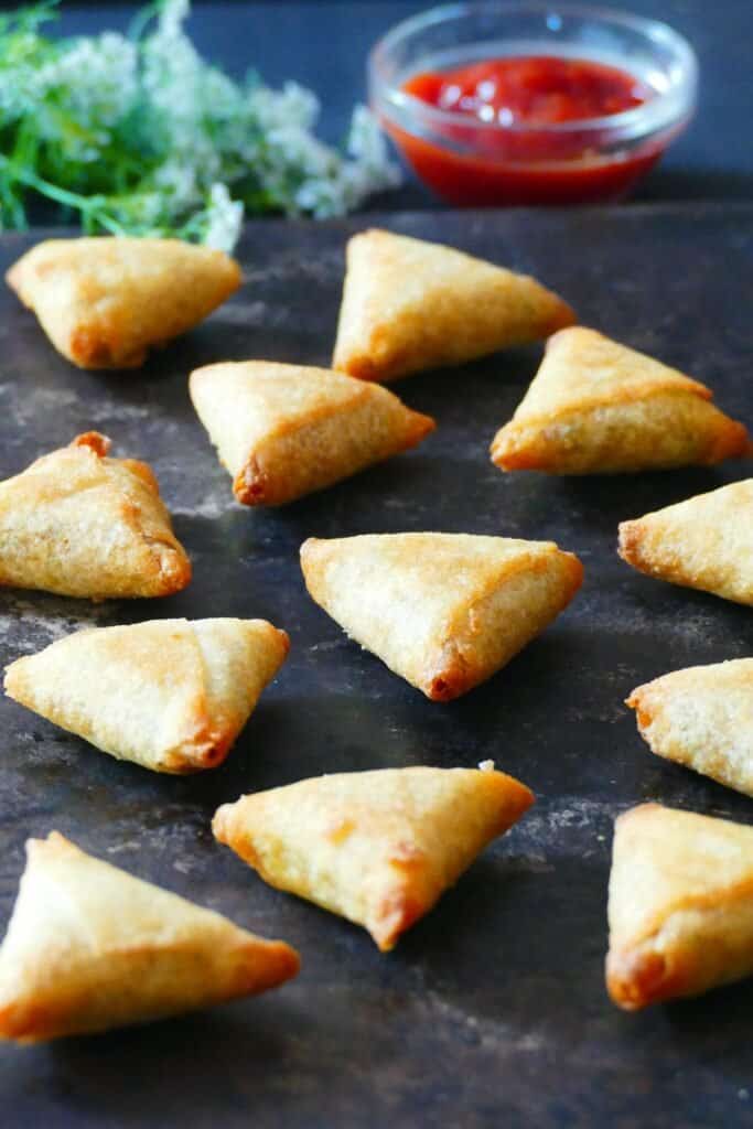 Golden mini samosas on dark background