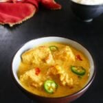 Instant Pot Fish Curry in a dark bowl with rice in background
