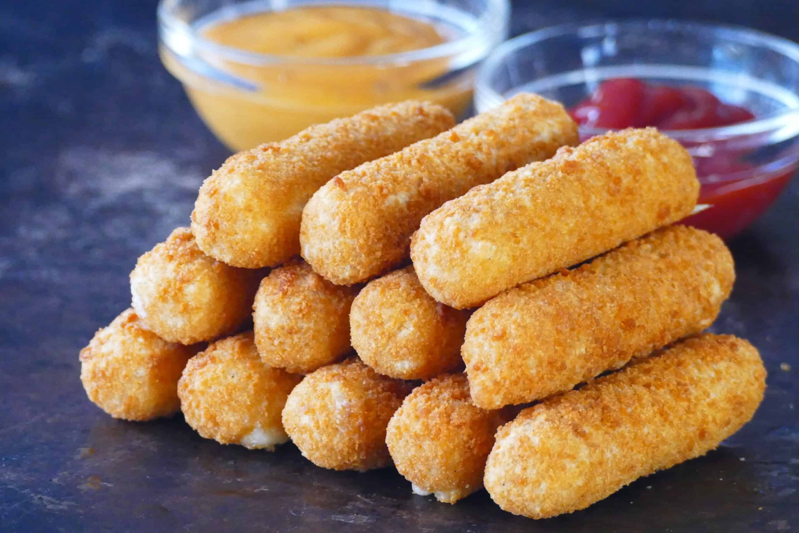 mozzarella sticks stacked on each other on dark surface