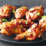 Cooked chicken wings on black plate garnished with parsley