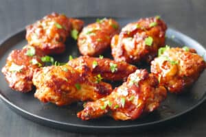 Cooked chicken wings on black plate garnished with parsley