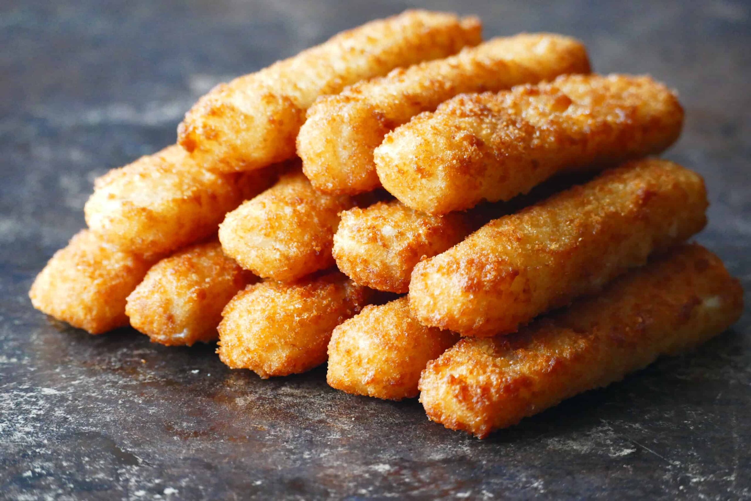 fish sticks stacked on each other on dark surface