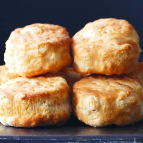 Golden biscuits stacked on a dark surface.