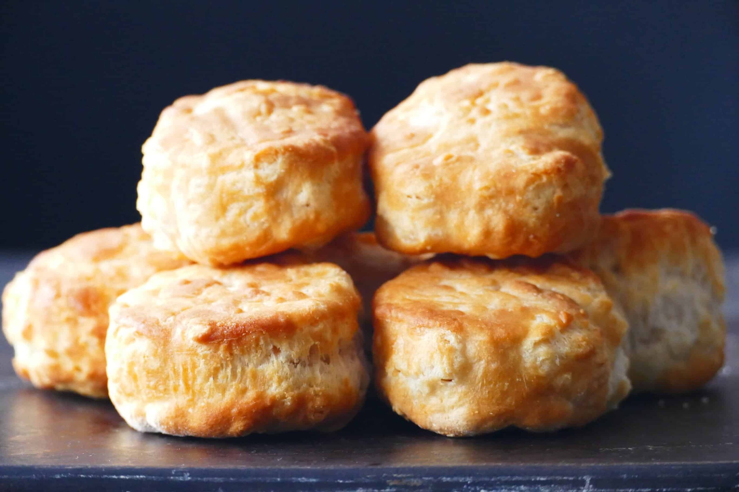 Golden biscuits stacked on a dark surface.