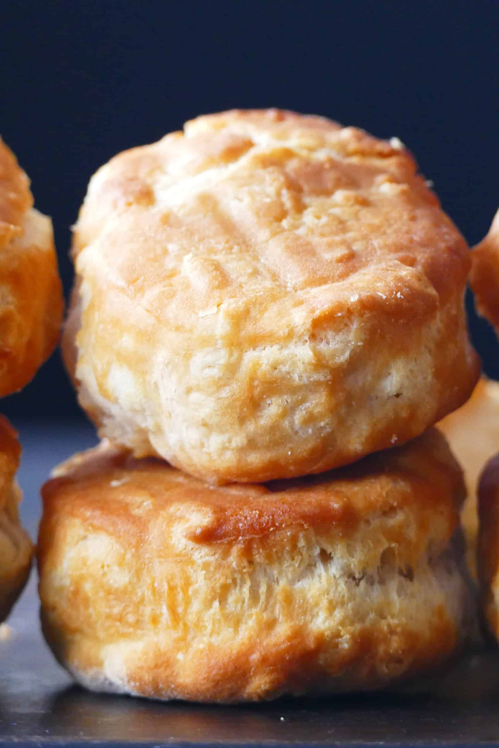 Air fryer frozen biscuits - Golden biscuits stacked on a dark surface.