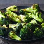 Black plate with slightly charred broccoli florets.