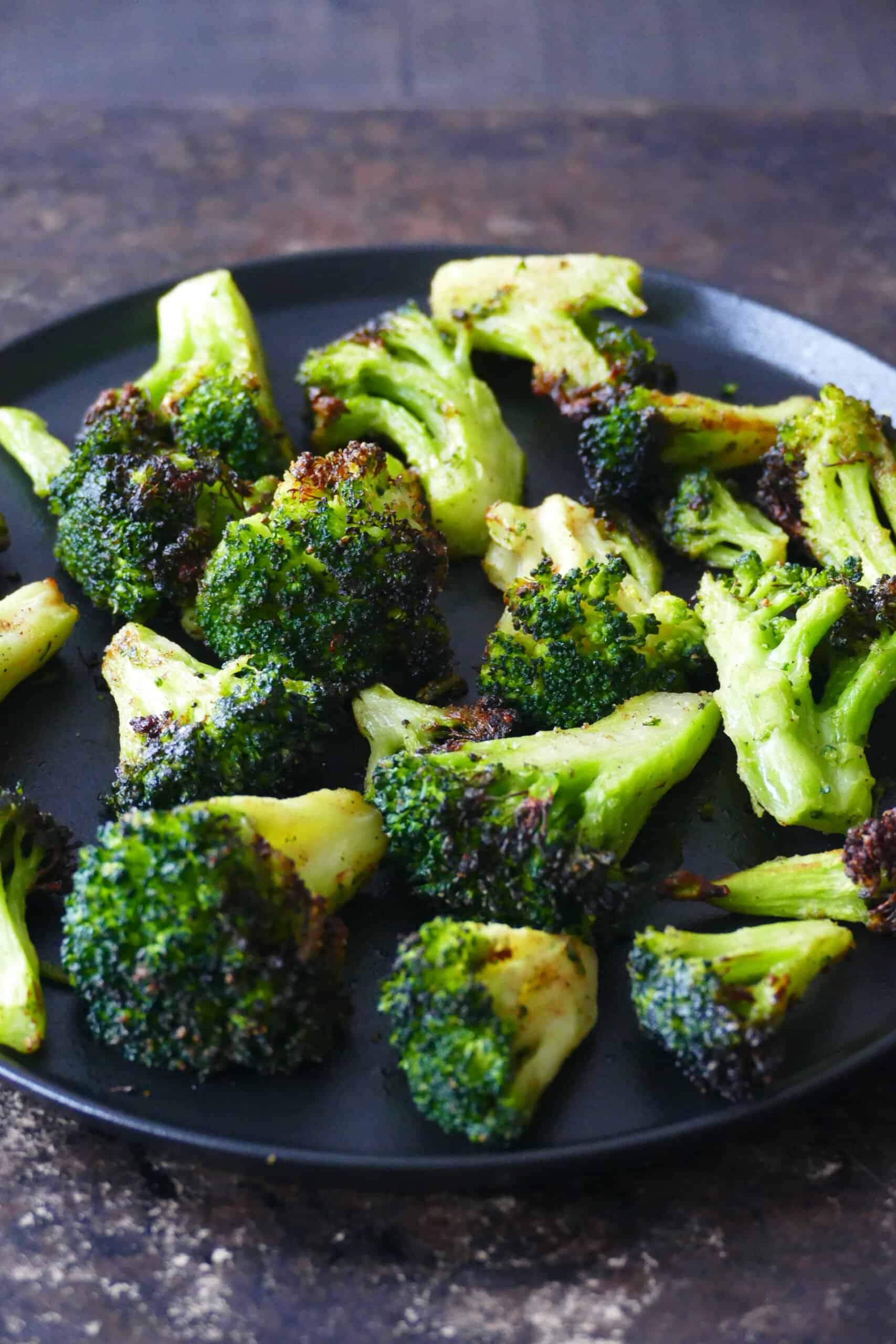 Black plate with slightly charred broccoli florets.