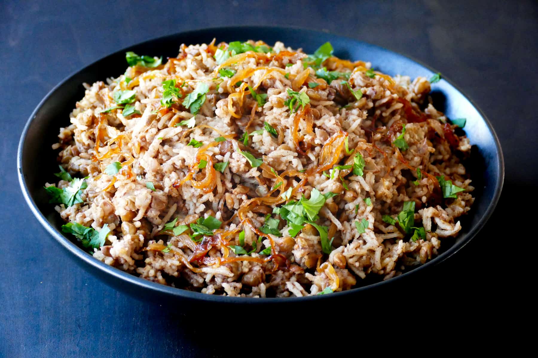 Black bowl with rice, lentils, onions and parsley