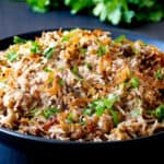 Black bowl with rice, lentils, onions and parsley