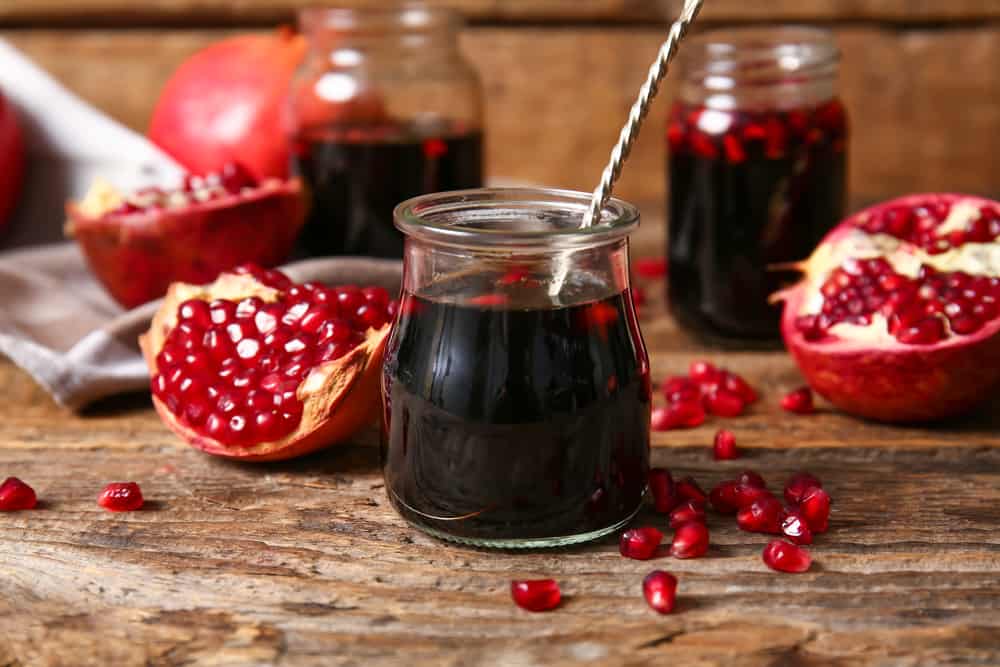 Jar of pomegranate molasses on wooden background