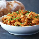 Creamy curry pasta with Indian masala in a white bowl.