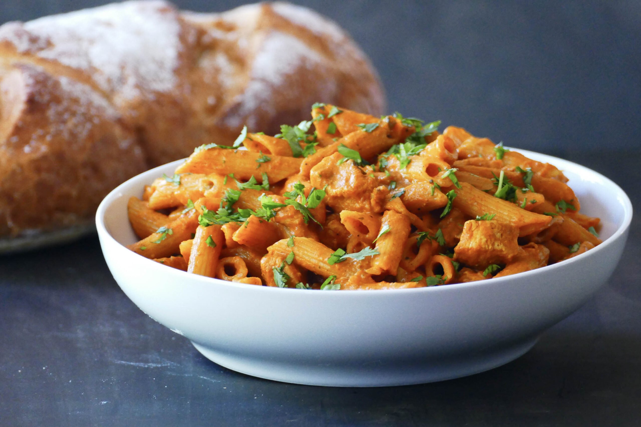 Creamy curry pasta with Indian masala in a white bowl.