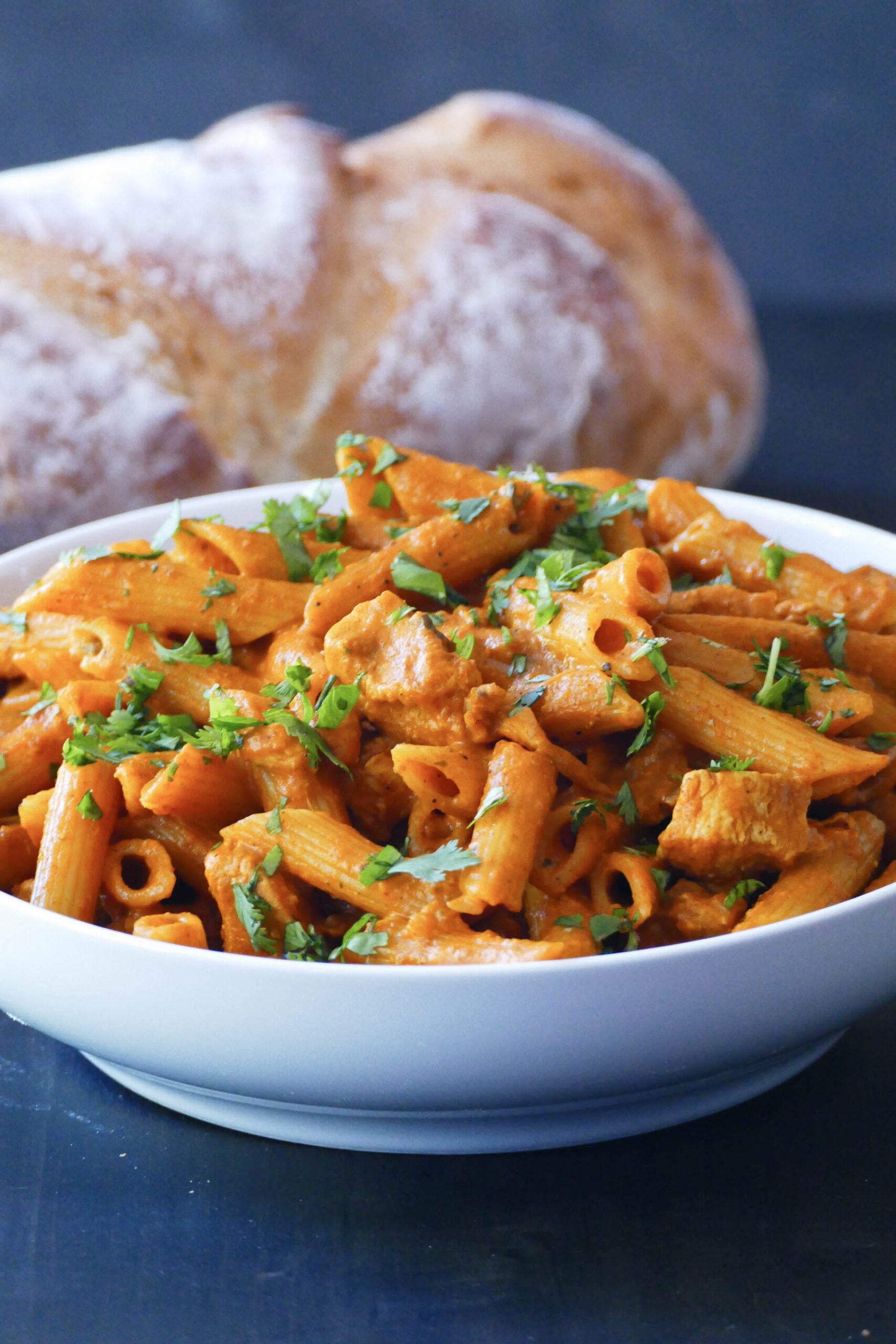 Creamy curry pasta with Indian masala in a white bowl.
