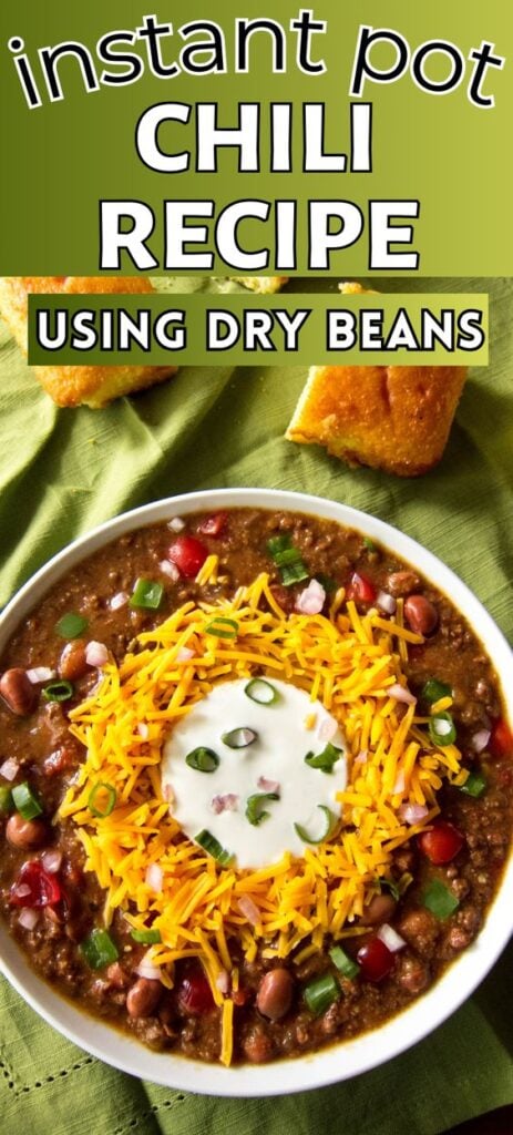 Instant Pot Chili Pinterest pin with image of chili with shredded cheddar surrounding sour cream, topped with green onions with text "instant pot chili recipe using dry beans".