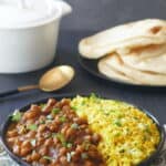 Instant Pot chana masala chickpea curry in a black bowl with yellow rice.