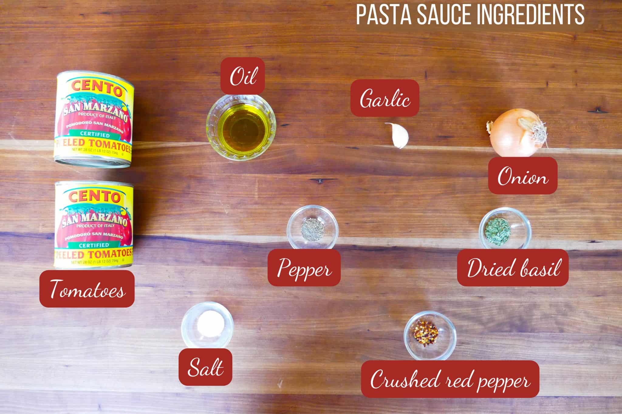 san marzano tomato sauce ingredients on a wood background - tomatoes, onion, garlic, oil, pepper, salt, basil, crushed red pepper.