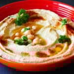 Hummus in bowl with chickpeas and parsley.