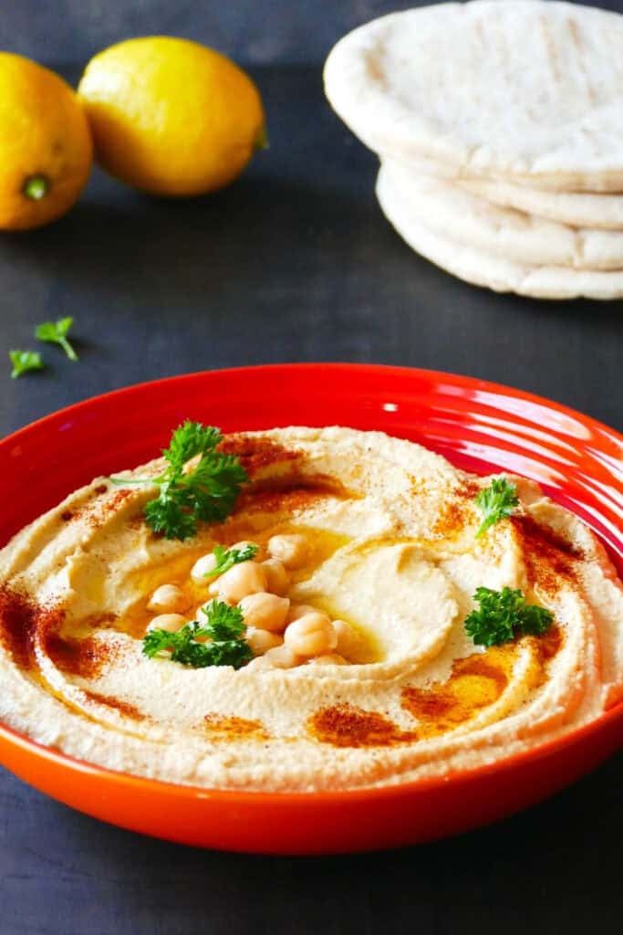 Hummus in bowl with chickpeas and parsley.