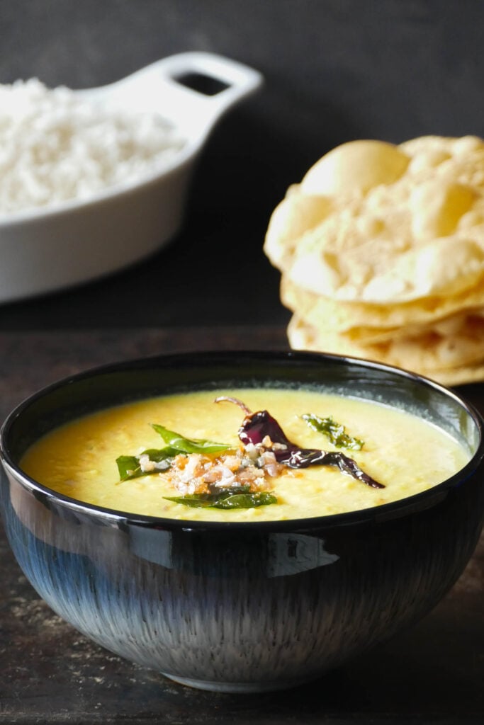 Bowl of Kerala parippu curry with fried curry leaves, onions, and chili.
