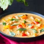 Bowl of Thai red curry with vegetables, chicken and Thai basil.