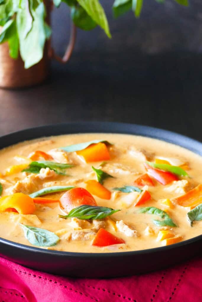 Bowl of Thai red curry with vegetables, chicken and Thai basil.