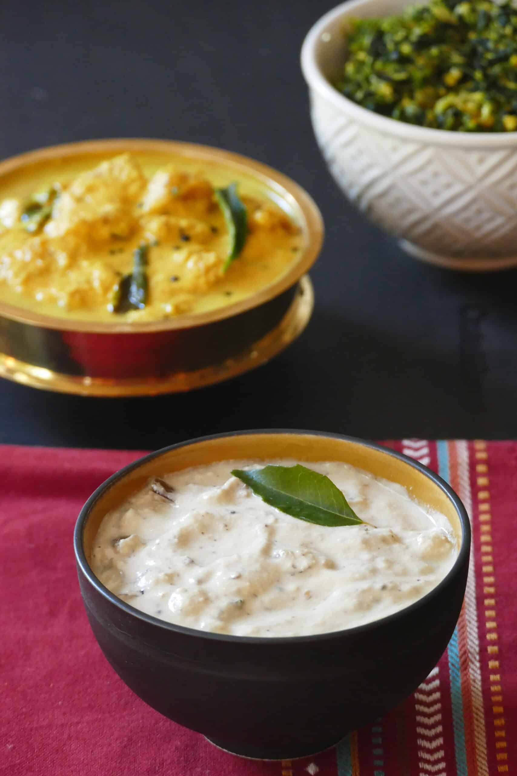 Cucumber kichadi in brown bowl with curry leaf on top.