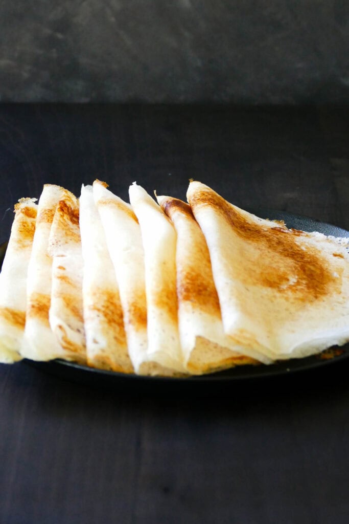 Dosa stacked overlapping on a plate.