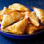 Golden beef and cheese empanadas on a blue plate.