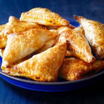 Golden beef and cheese empanadas on a blue plate.