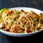 Pad Thai with chicken shrimp and tofu in white bowl.