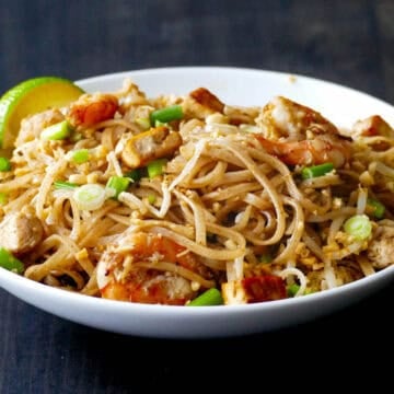 Pad Thai with chicken shrimp and tofu in white bowl.
