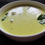 Moru curry with dried chilis and curry leaves in a white bowl.